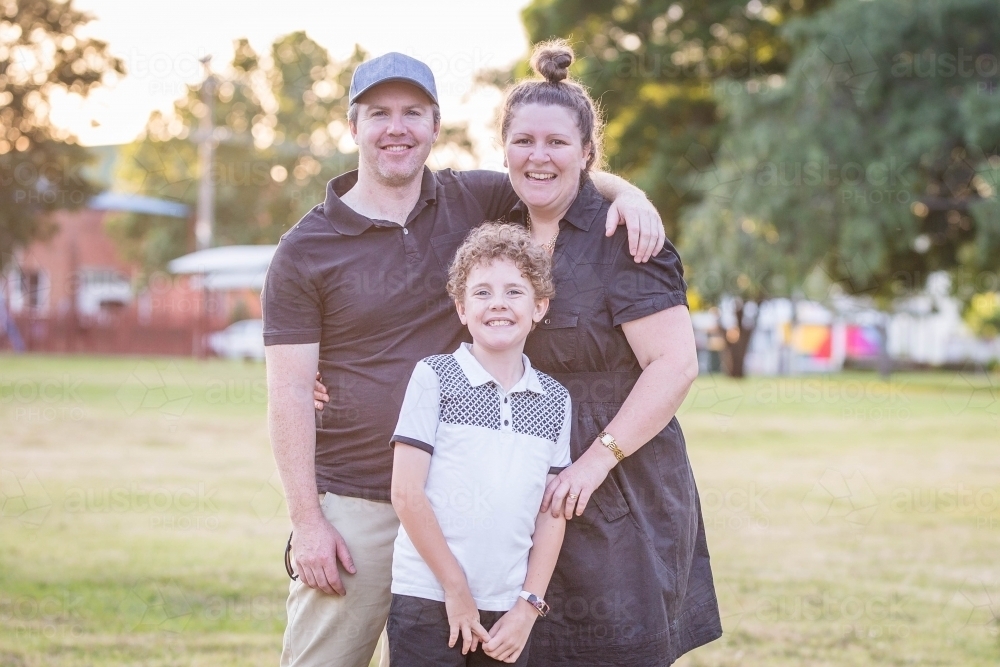 Family of a dad mum and son standing together smiling - Australian Stock Image