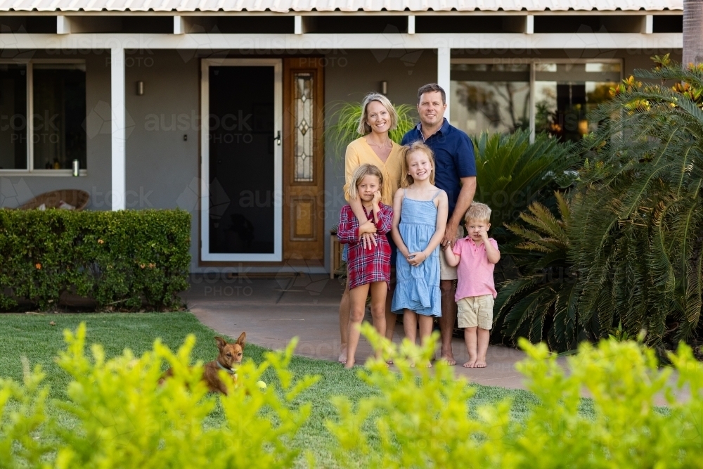 family of five posing in front of their home - Australian Stock Image