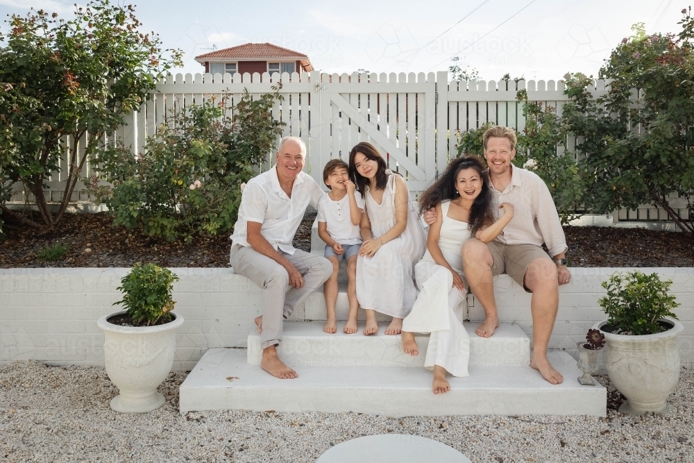 Family of five sitting on backyard steps - Australian Stock Image