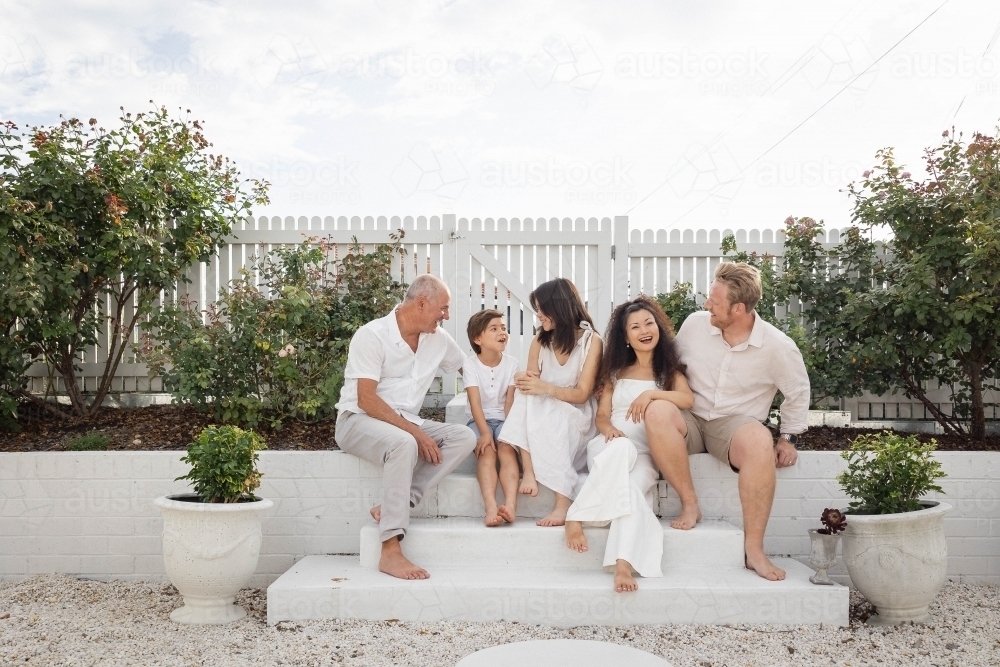 Family of five sitting on backyard steps - Australian Stock Image