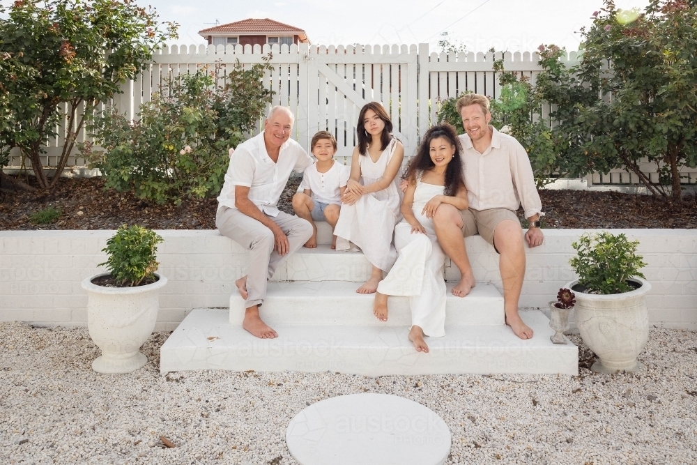 Family of five sitting on backyard steps - Australian Stock Image
