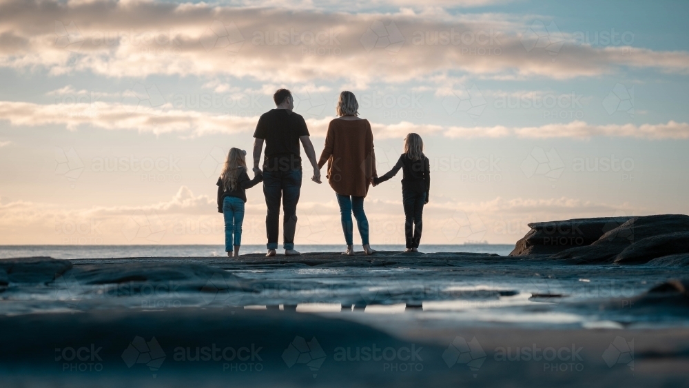 Family of four silhouette looking out at beach - Australian Stock Image