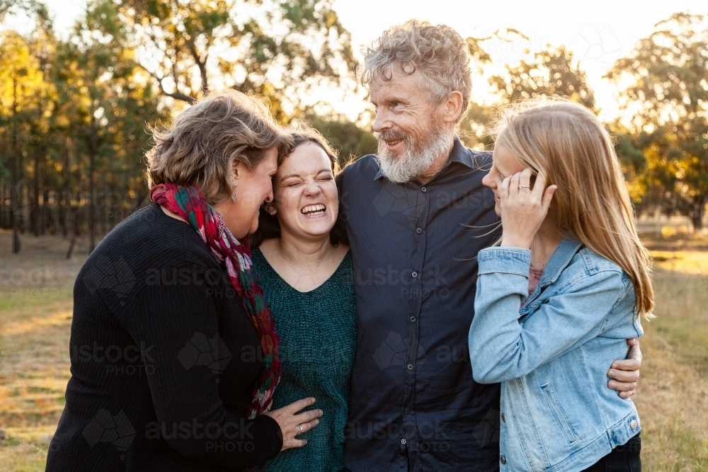 Family of four with adult children looking at one another laughing - Australian Stock Image