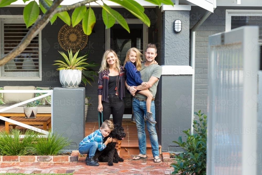 Family of four with pet dog in front of suburban home : Austockphoto Family of four with pet dog in front of suburban home - Australian Stock Image