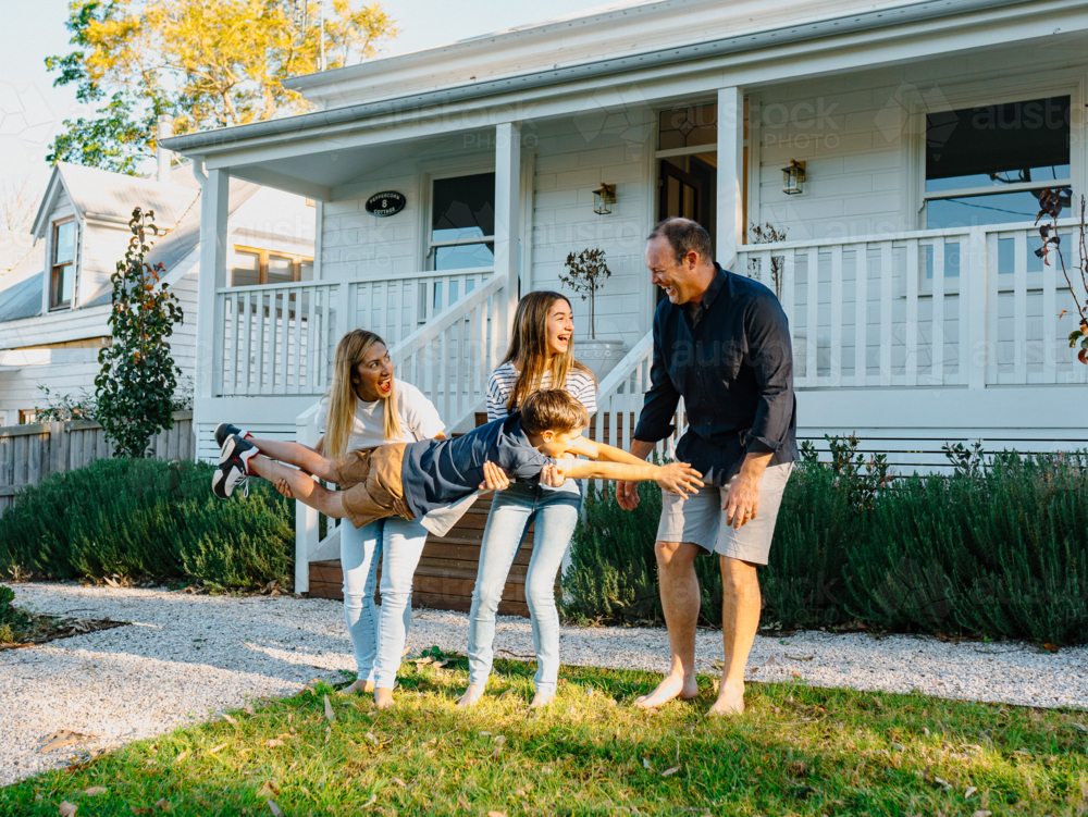 Family playing in the front yard of the house. - Australian Stock Image