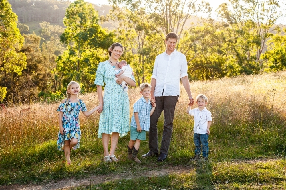 Family portrait of young family with four children on farm in paddock - Australian Stock Image