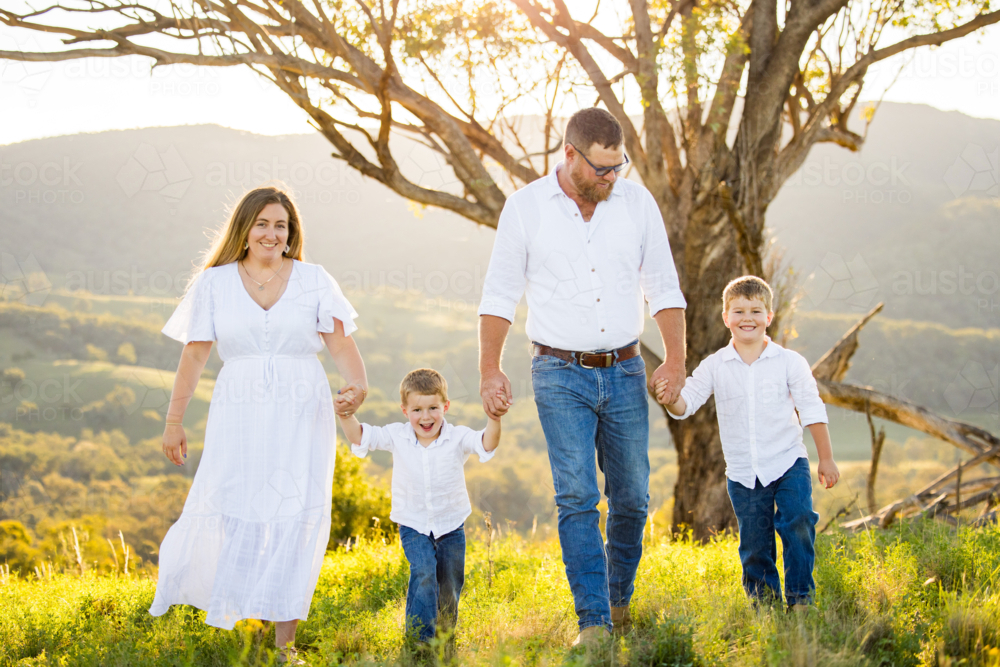 Family portrait on hilltop with lush green landscape at sunset - Australian Stock Image