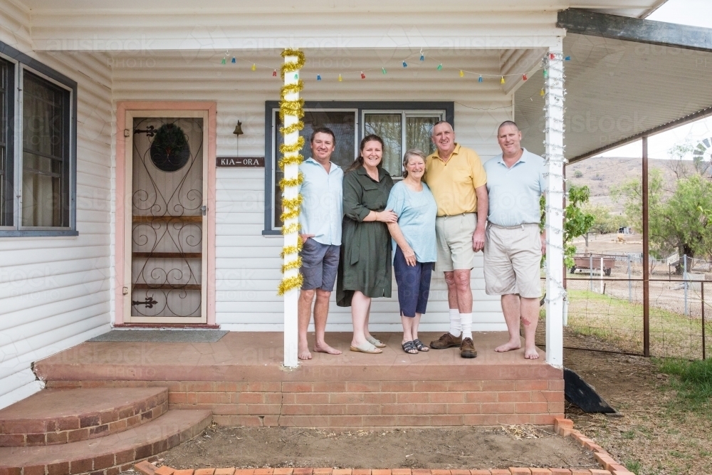 Family retired parents standing with adult children on front verandah of house - Australian Stock Image