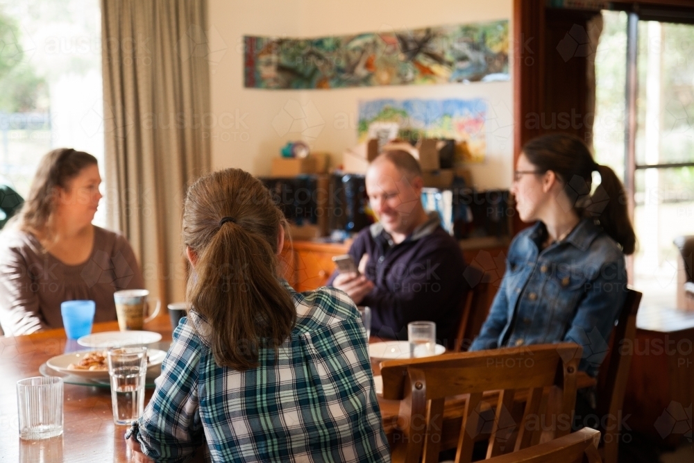 Family sitting together around a table inside - Australian Stock Image