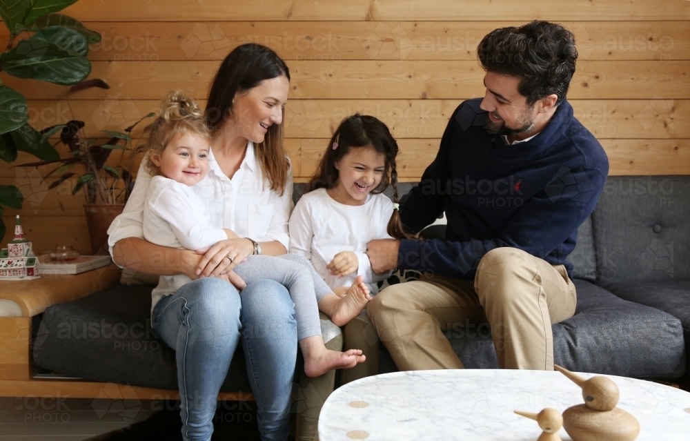 Family smiling and laughing together in lounge room : Austockphoto Family smiling and laughing together in lounge room - Australian Stock Image