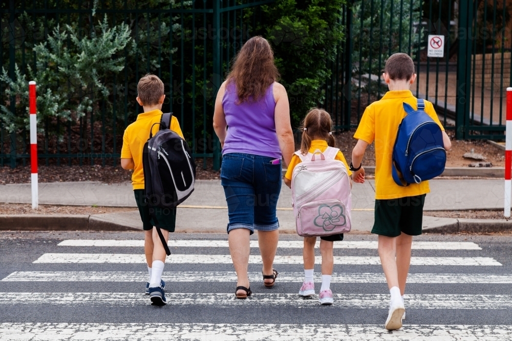 Family walking across pedestrian crossing to school - Australian Stock Image