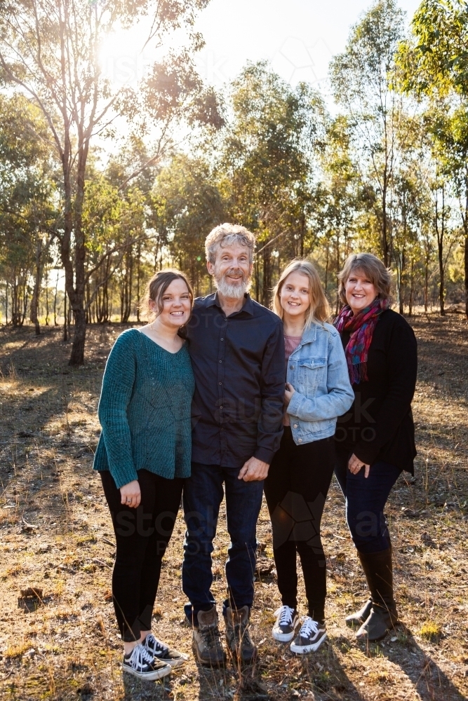 Family with teen and adult daughters standing together in paddock - Australian Stock Image