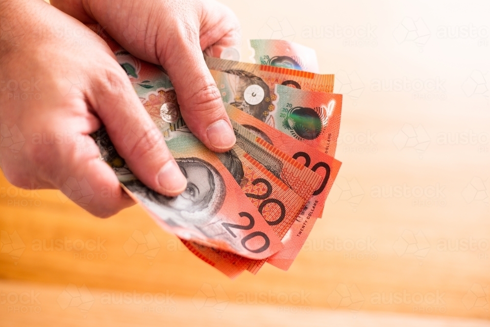 fanned out twenty dollar notes held with two hands - Australian Stock Image