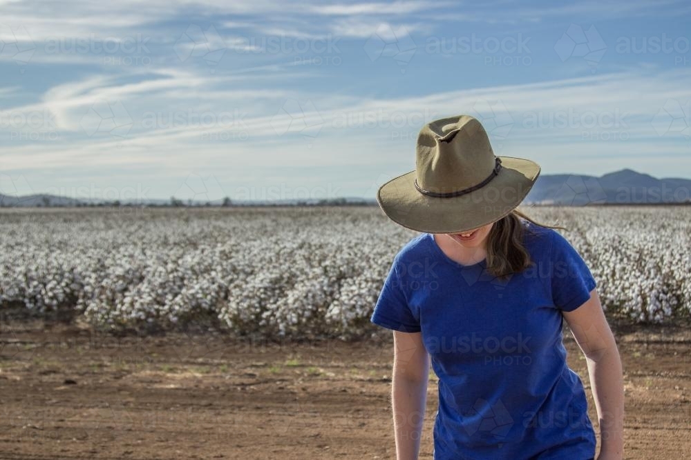 Farm girl walking away from a paddock of cotton - Australian Stock Image