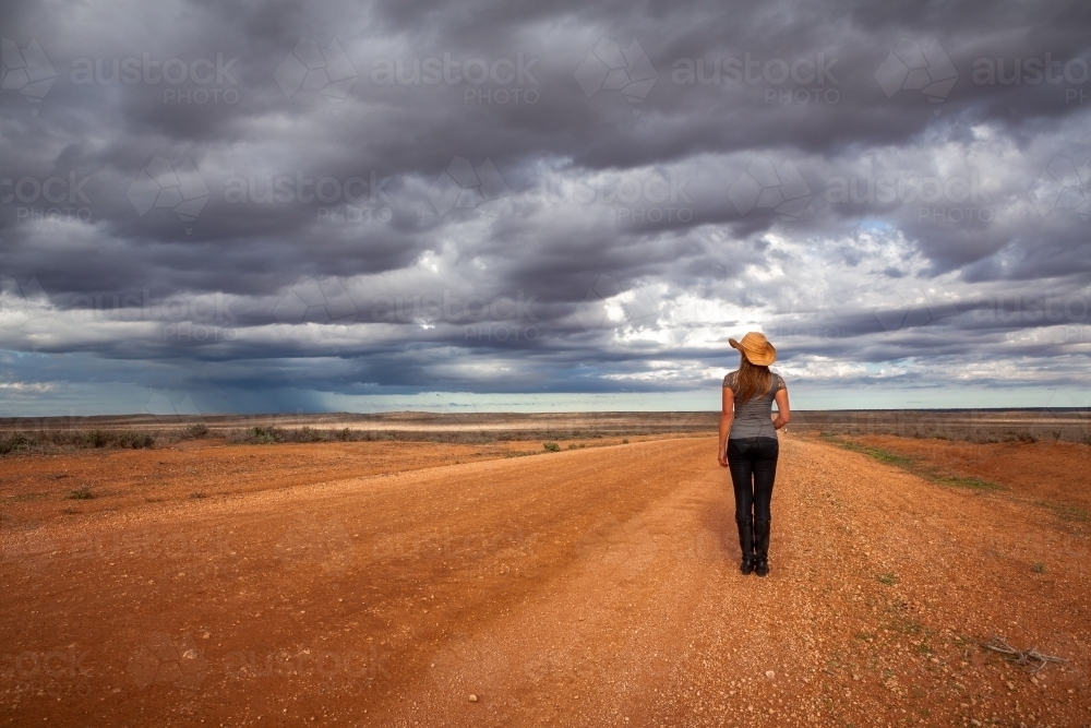 Farm woman watches the storm over an arid desert landscape outback Australia - Australian Stock Image
