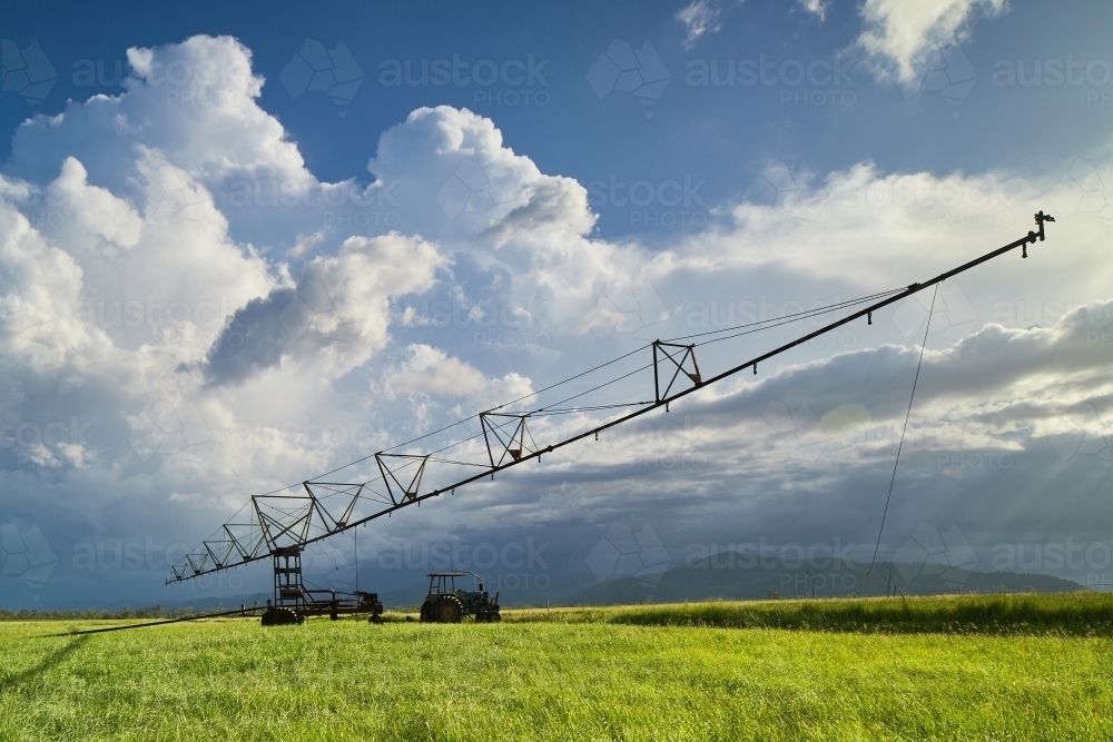 Farm irrigator sitting in paddock with storm clouds behind. - Australian Stock Image