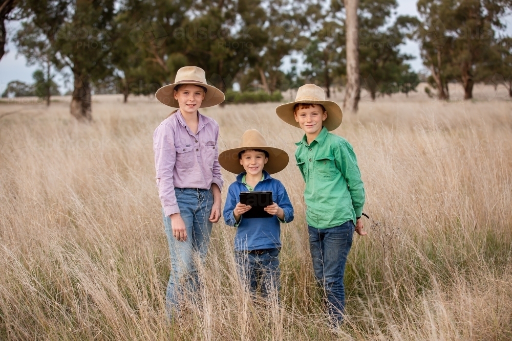 Farm kids in the paddock with an ipad - Australian Stock Image