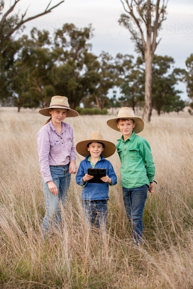 Farm kids using an ipad in the paddock - Australian Stock Image