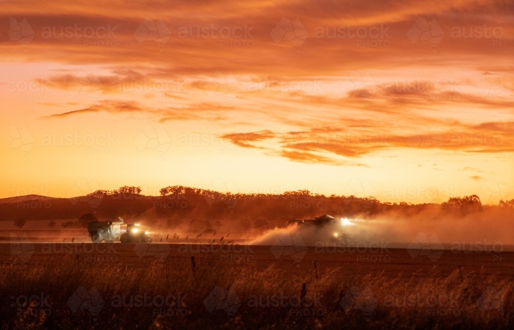 farm machinery harvesting crops at sunset - Australian Stock Image