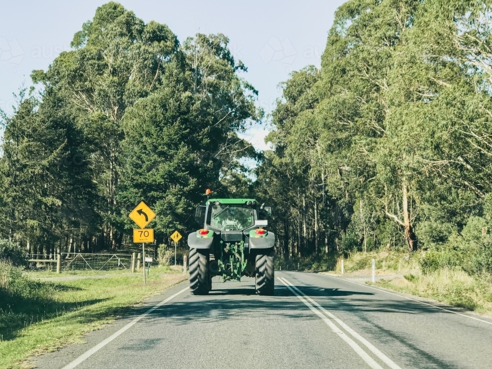 Image of Farm tractor driving on country road Austockphoto