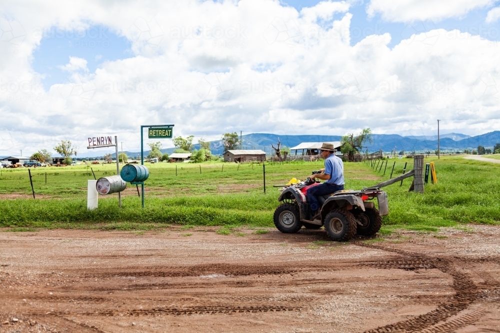 Farmer checking mail on quad bike - Australian Stock Image