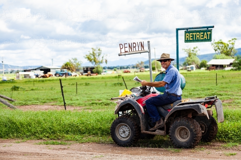 Farmer checking mail on quad bike - Australian Stock Image