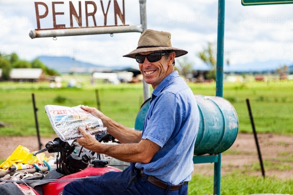 Farmer checking mail on quad bike - Australian Stock Image