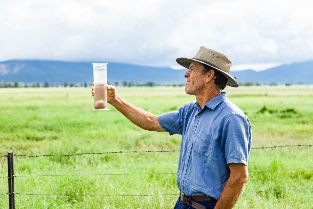 Farmer checking rain in bureau of meteorology rain gauge - Australian Stock Image