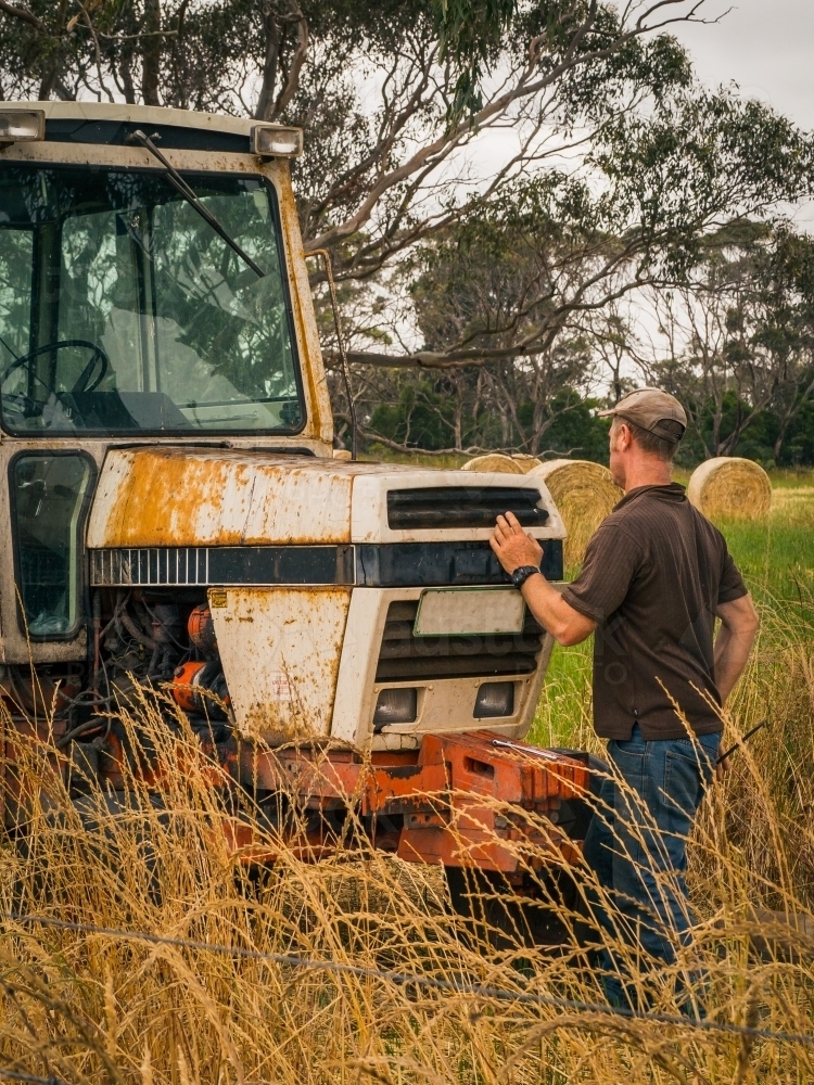Farmer fixing old tractor during hay season - Australian Stock Image