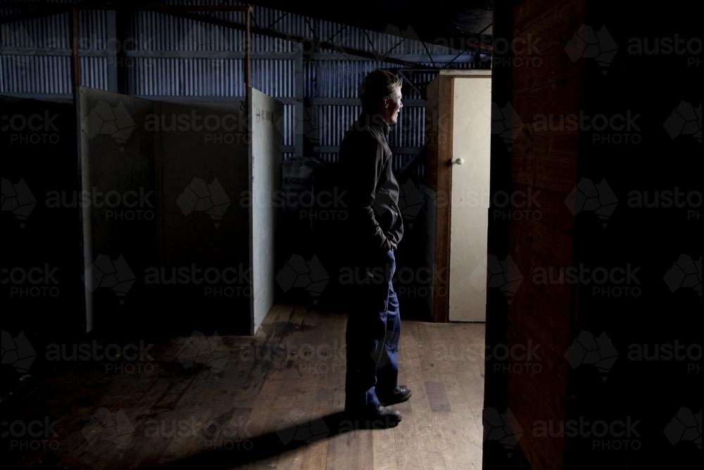 Farmer in dark shearing shed - Australian Stock Image