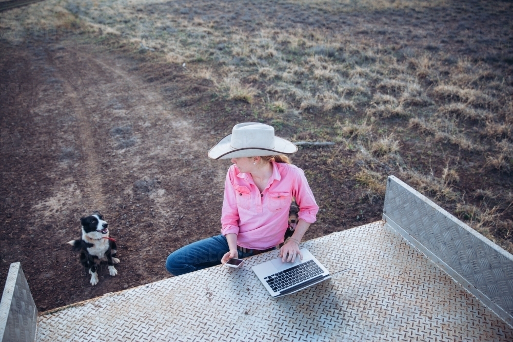 Farmer looking at dog while touching laptop - Australian Stock Image