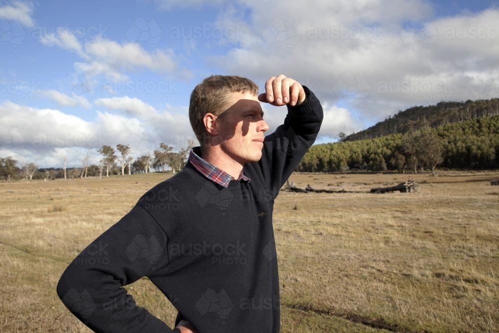 Farmer looking away in the distance at property - Australian Stock Image