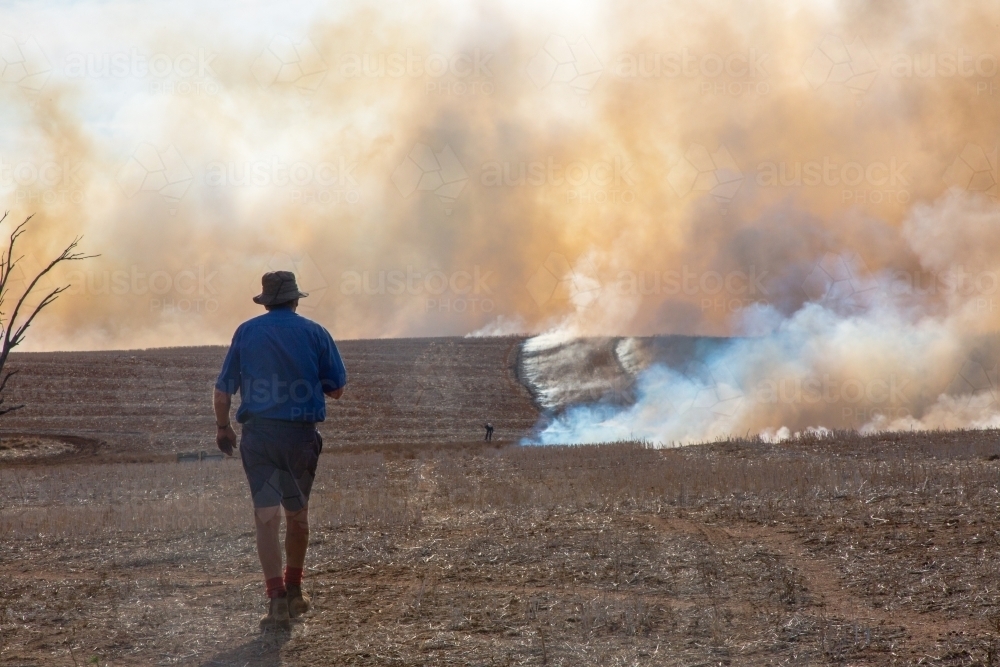 Farmer watching a fire burning canola stubble - Australian Stock Image