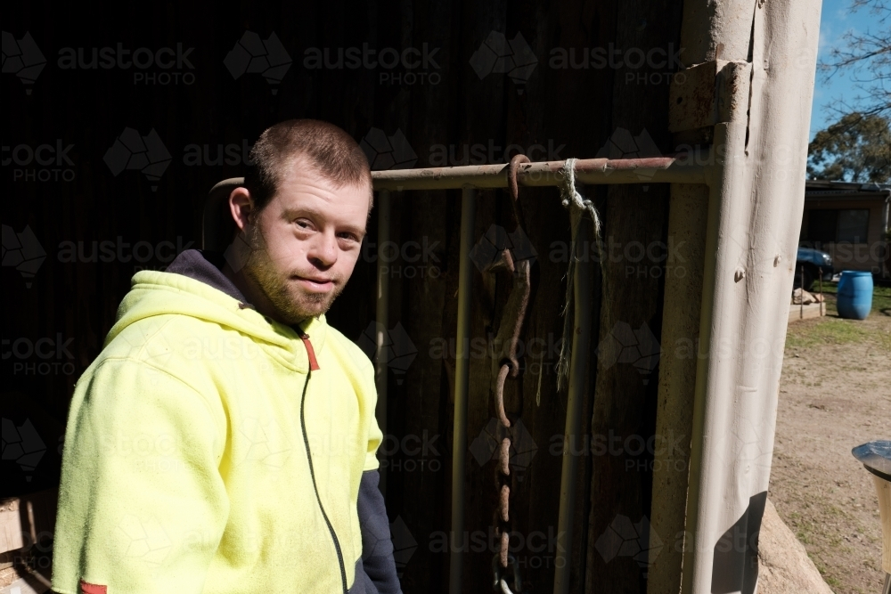 Farmhand with yellow jacket standing outside a Farm Shed - Australian Stock Image