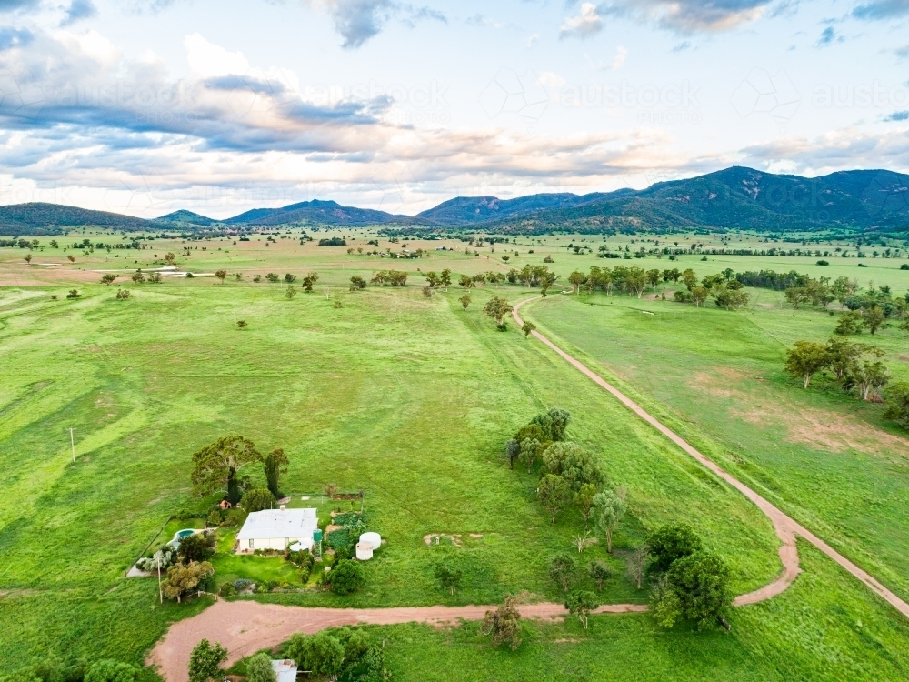 Farmhouse at the end of long driveway and green farm paddocks at dusk - Australian Stock Image