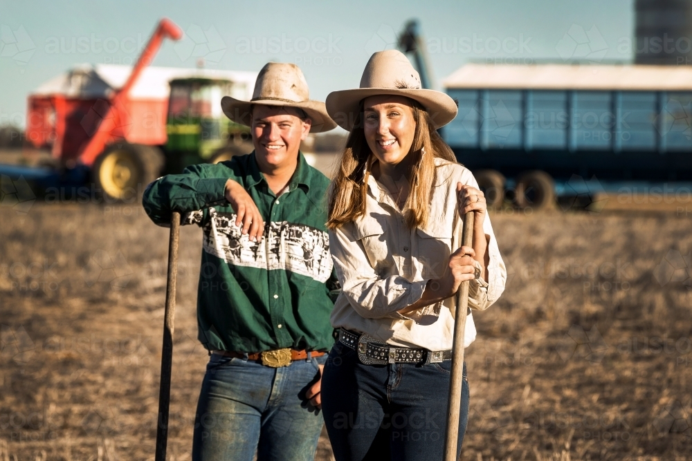 Farming couple with tools and machinery in the background - Australian Stock Image