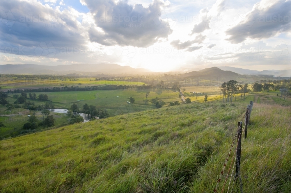 Farmland vista with fence looking into the light - Australian Stock Image