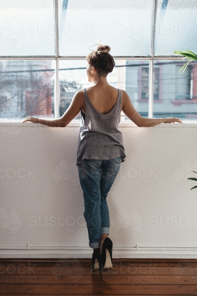 Fashion designer watching from her studio window - Australian Stock Image