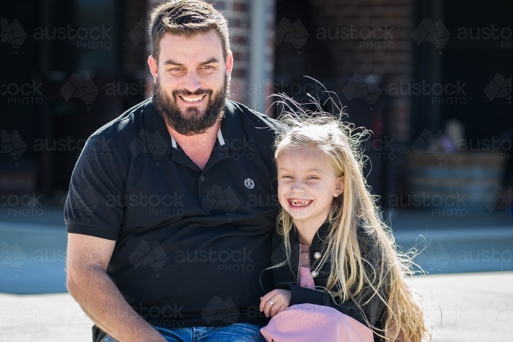 Father and daughter cuddling up together laughing - Australian Stock Image