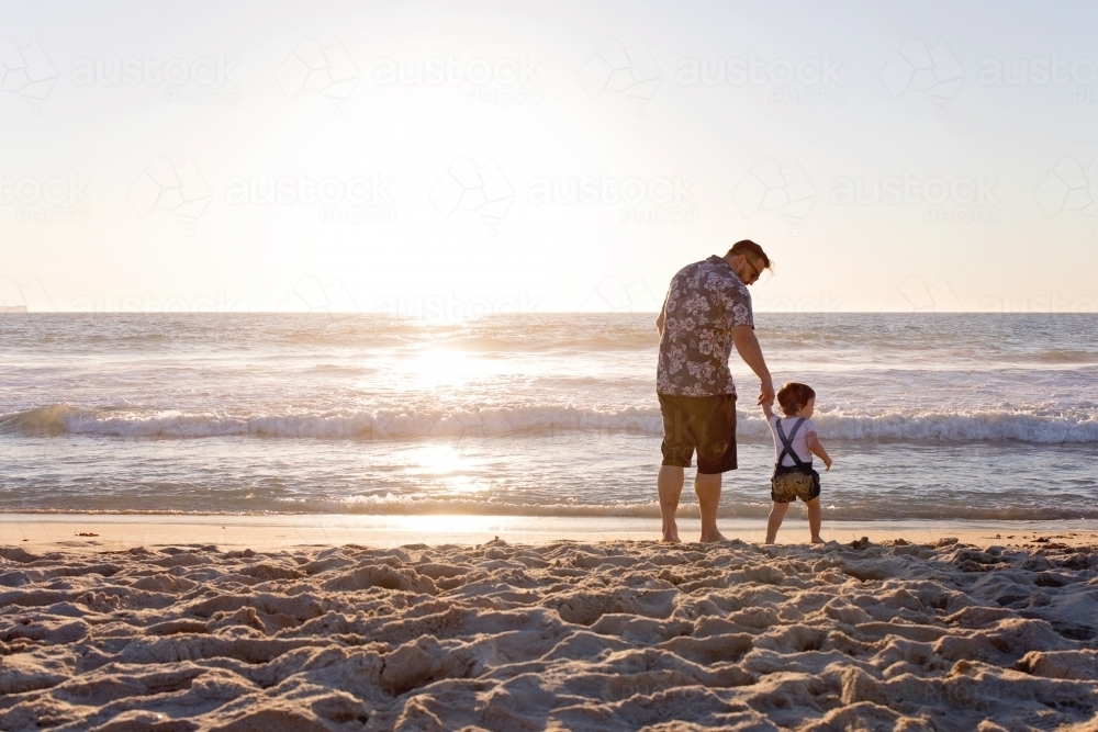 Father And Daughter Holding Hands On the Beach At Sunset - Australian Stock Image