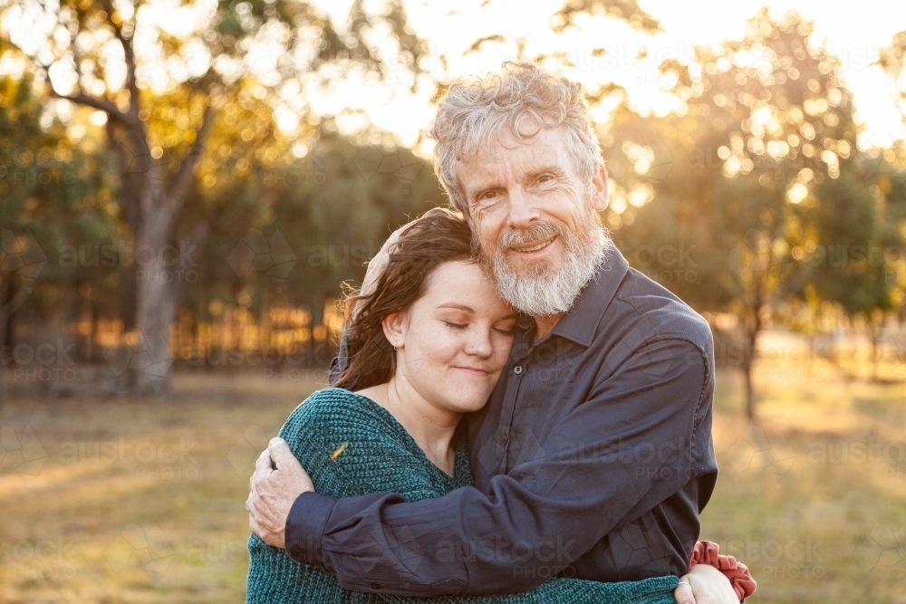 Father and daughter hug in afternoon light - Australian Stock Image