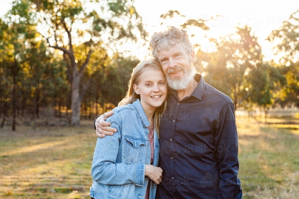 Father and daughter hug together in paddock with copy space - Australian Stock Image
