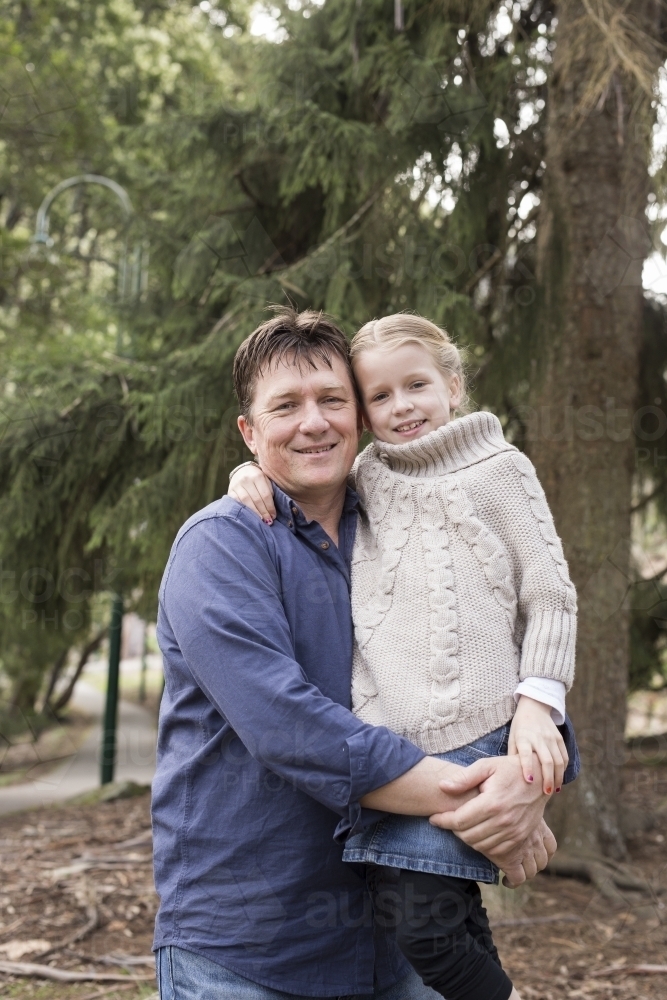 Father and daughter hugging outdoors - Australian Stock Image