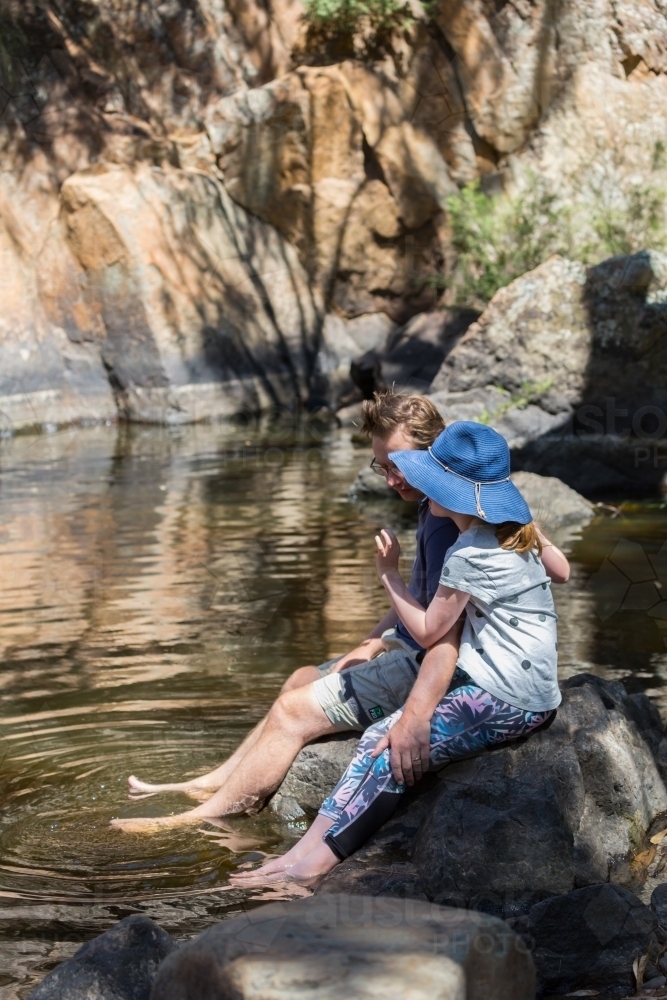Father and daughter sitting near a waterhole in inland Australia - Australian Stock Image
