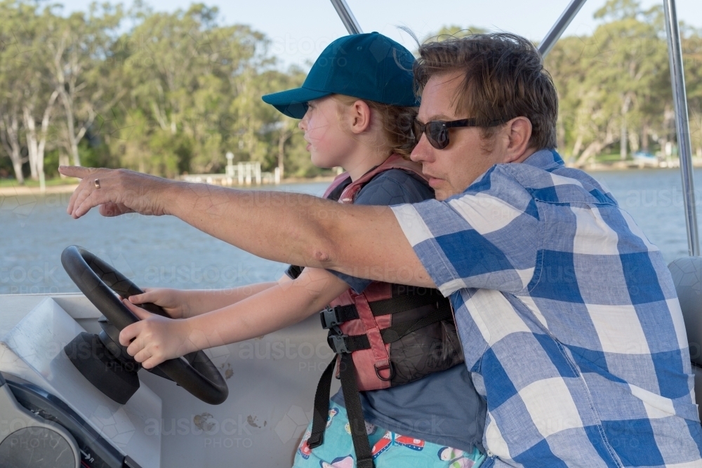 father and daughter steering a boat together - Australian Stock Image