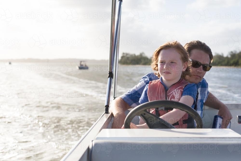 father and daughter steering a boat together - Australian Stock Image