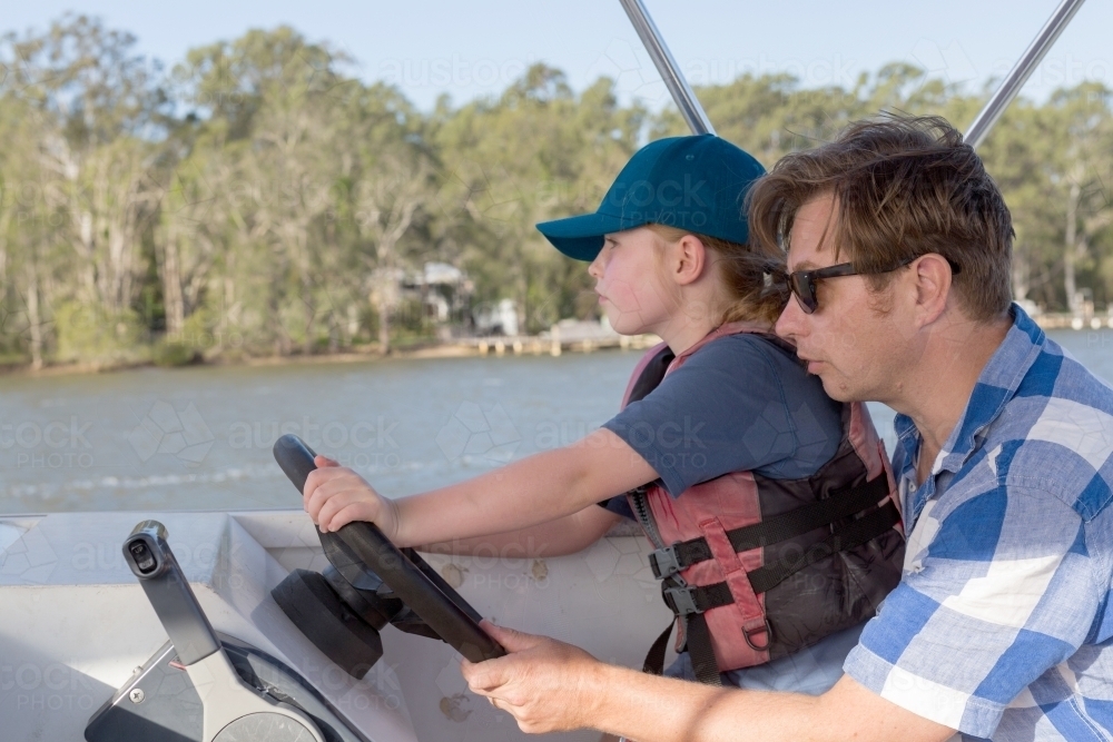 father and daughter steering a boat together - Australian Stock Image