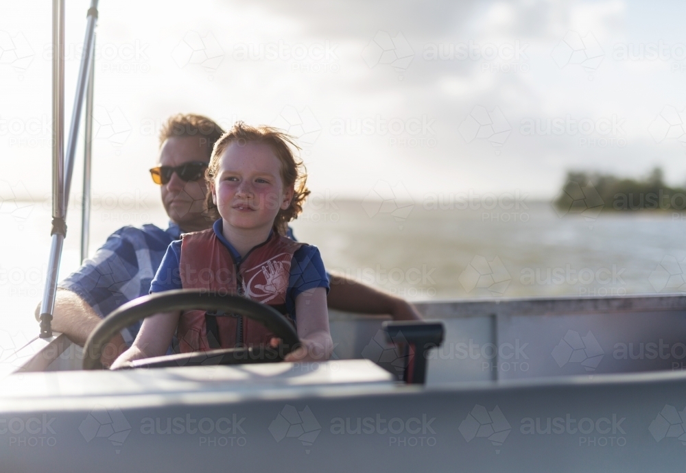 Father and daughter steering a boat together - Australian Stock Image