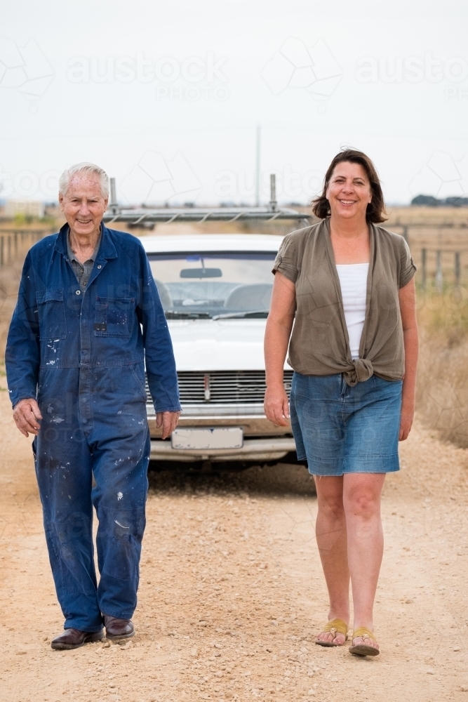 Father and daughter walk on a country back road. - Australian Stock Image