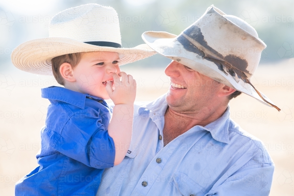 Father and son laughing in farm setting - Australian Stock Image